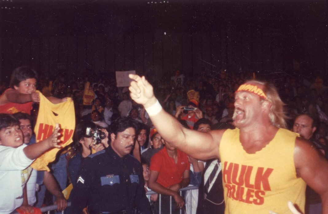 Hulk Hogan waving to cheering fans in a packed arena.